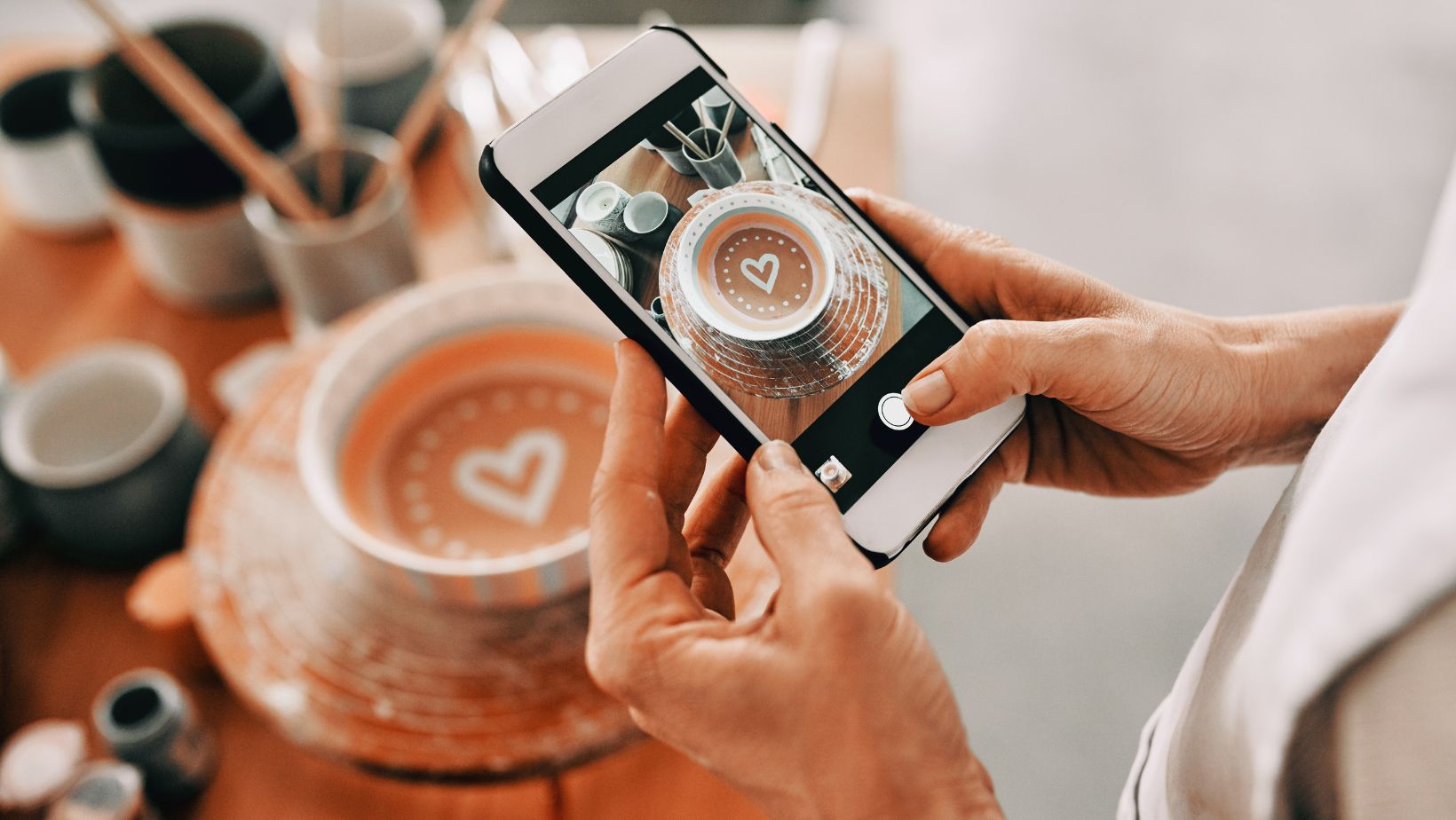 Hands holding a phone to take a picture of a cup of coffee for advantages and disadvantages of social media.