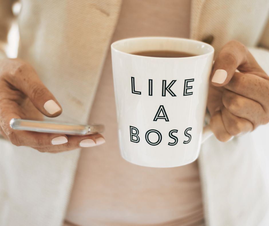 An empty nest woman holding a phone and a cup of coffee saying Like a Boss.