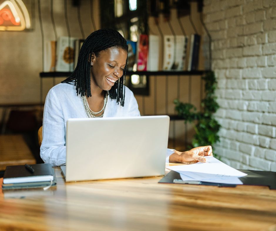 Image of a woman sitting at her computer smiling and beginning a blog.