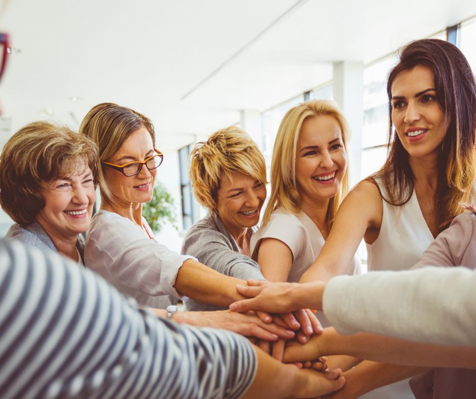 A group of women with hands in the center for a Female Entrepreneurs meet up.