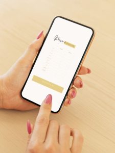 A female hand with pink nails holding a phone and downloading the Persona Creator.