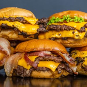 2024 Best Burgers in Tampa image featuring a stack of cheesy, juicy burgers on a black countertop.