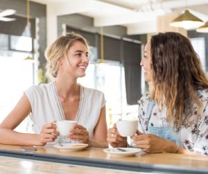 Image of 2 women happily talking over coffee.