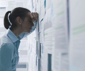Overcoming fear of failure woman laying her head on a wall of papers.